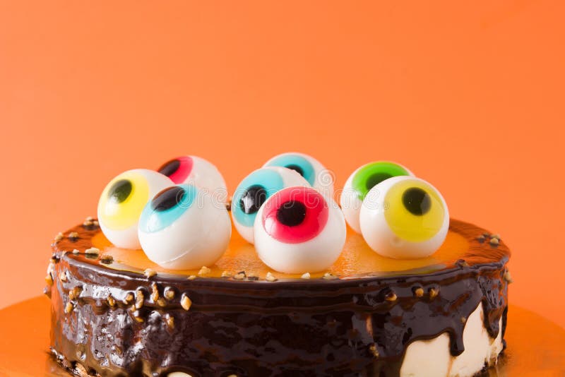 Halloween cake with candy eyes decoration on wooden table. Close