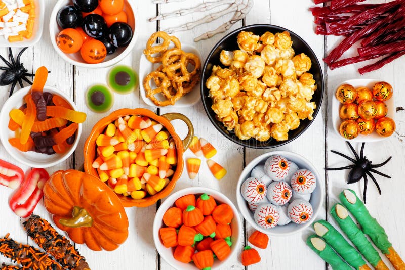 Halloween candy buffet table scene over a white wood background. Selection of fun, spooky treats. Top view