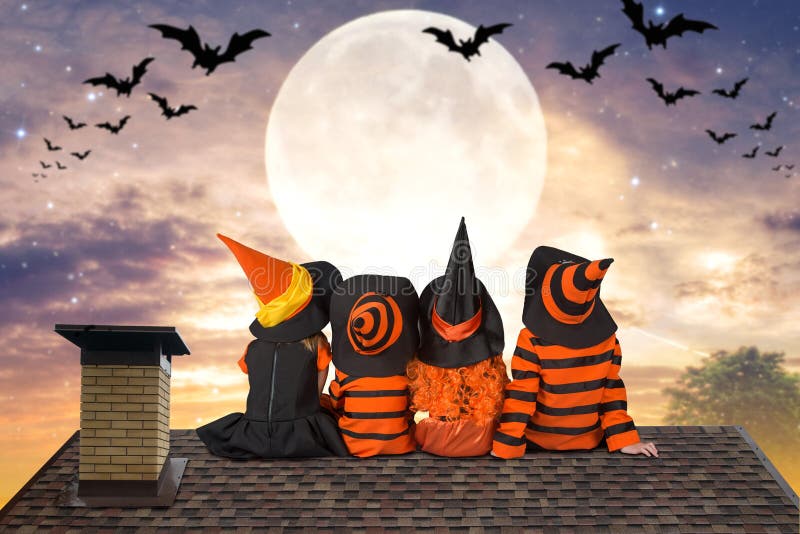 Halloween.Children in costumes of witches and wizard are sitting that night on the roof and look at the sky and bats