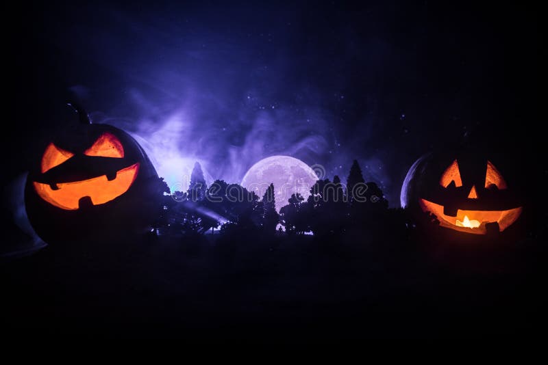 Halloween concept with glowing pumpkins. Strange silhouette in a dark spooky forest at night, mystical landscape surreal lights with creepy man. Selective focus