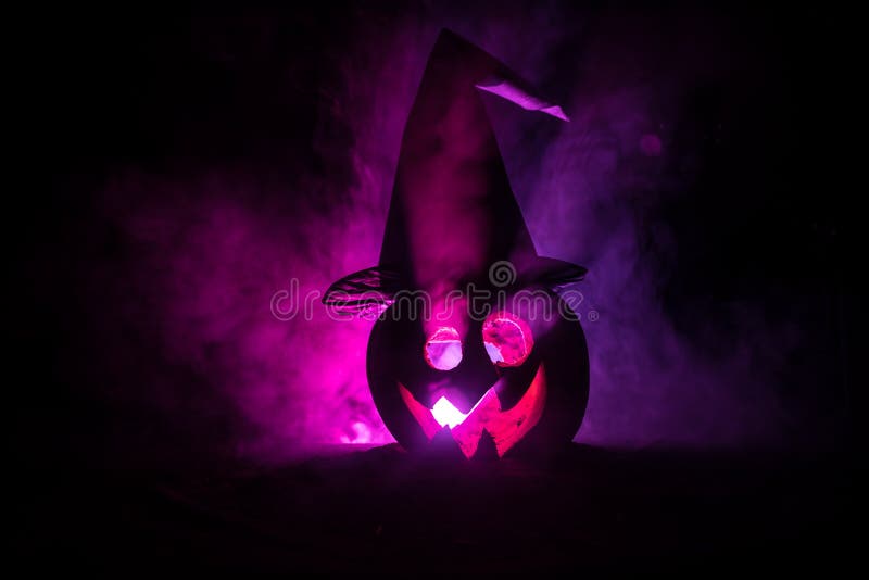 Halloween concept. Jack-o-lantern smile and scary eyes for party night. Close up view of scary pumpkin with witch hat on at dark f stock images Halloween concept. Jack-o-lantern smile and scary eyes for party night. Close up view of scary pumpkin with witch hat on at dark f stock images