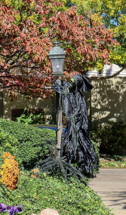 Halloween decoration-Grim Reaper hangs on Lamp pole with giant spider at his feet