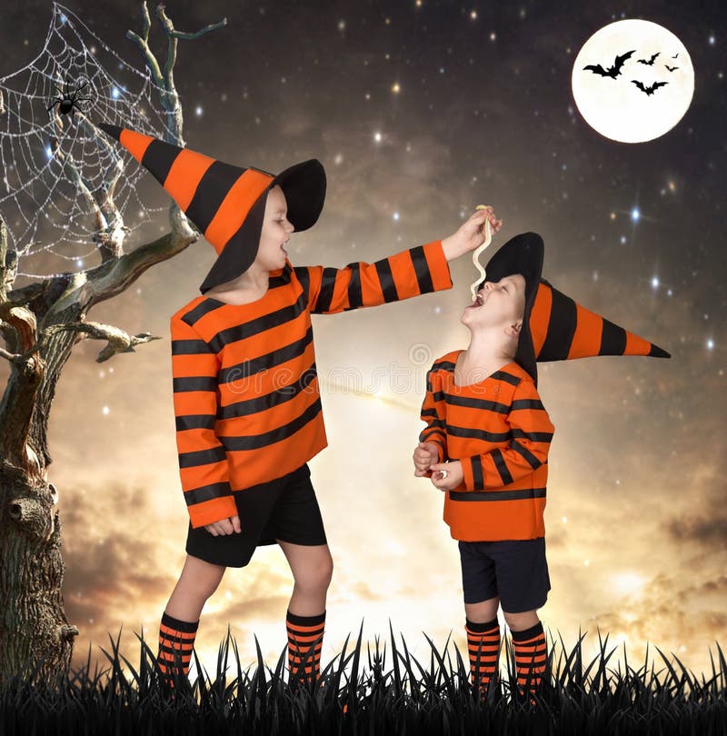 Halloween Due fratelli in costume che camminano nell'legno spaventoso Il ragazzo alimenta il suo serpente del fratello fotografia stock Halloween Due fratelli in costume che camminano nell'legno spaventoso Il ragazzo alimenta il suo serpente del fratello fotografia stock