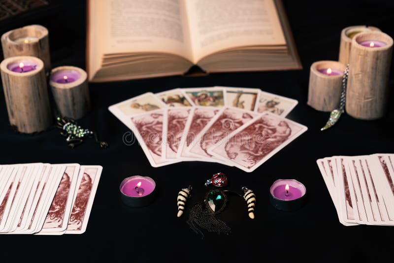 Candles and old tarot cards on black silk. Halloween and fortune telling concept. Mystic background with occult and magic objects on witch table. Candles and old tarot cards on black silk. Halloween and fortune telling concept. Mystic background with occult and magic objects on witch table