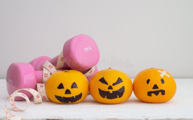 Halloween Festical with Fitness, Exercise, Working out, weight and dieting, healthy lifestyle background concept. Fresh Orange with Head Pumpkins haunted spooky face easy DIY decoration with dumbbells and tape measure on white wood. Halloween Festical with Fitness, Exercise, Working out, weight and dieting, healthy lifestyle background concept. Fresh Orange with Head Pumpkins haunted spooky face easy DIY decoration with dumbbells and tape measure on white wood.