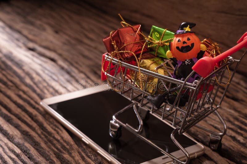 Halloween festival online mobile shopping concept. Halloween pumpkins with shopping cart and smartphone on wood background. royalty free stock photo Halloween festival online mobile shopping concept. Halloween pumpkins with shopping cart and smartphone on wood background. royalty free stock photo