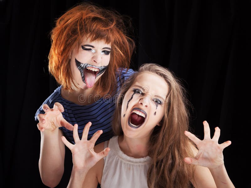 Portrait of Two girls makeup up for celebrating Halloween, on a black background. Portrait of Two girls makeup up for celebrating Halloween, on a black background