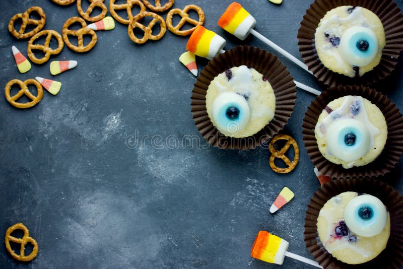 Halloween fun food - eye muffins, cookies, candy corn, marshmallow pops on a stone background top view