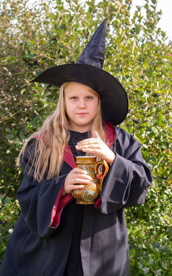Halloween. a Girl in a Robe and Hat. a Little Sorceress in the