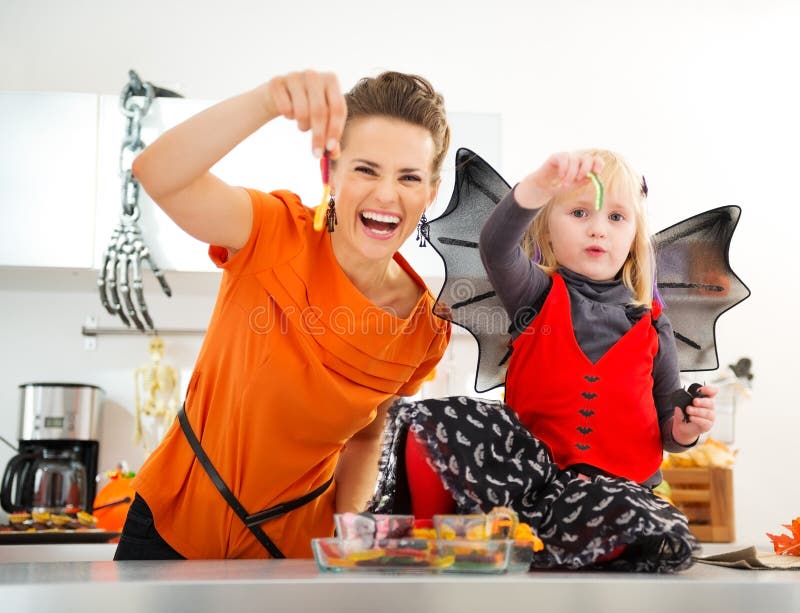 Halloween a habillé la fille avec la mère montrant les sucreries gommeuses de ver photo libre de droits Halloween a habillé la fille avec la mère montrant les sucreries gommeuses de ver photo libre de droits