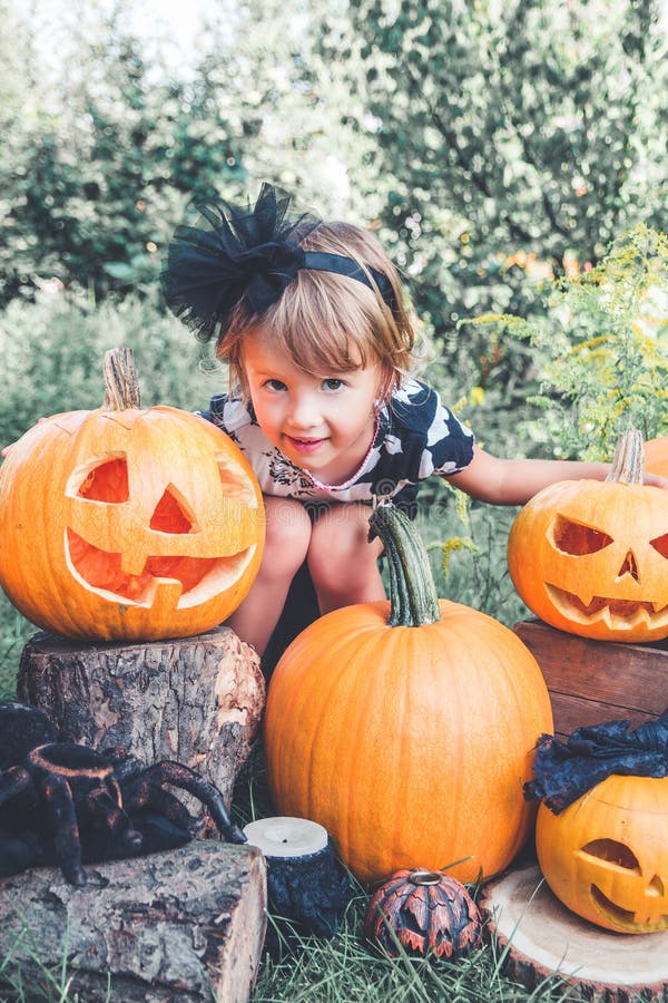 Halloween Het kind kleedde zich in zwarte dichtbij Labrador tussen hefboom-o-lantaarn decoratie, truc of behandelt Meisje met hon stock fotografie Halloween Het kind kleedde zich in zwarte dichtbij Labrador tussen hefboom-o-lantaarn decoratie, truc of behandelt Meisje met hon stock fotografie