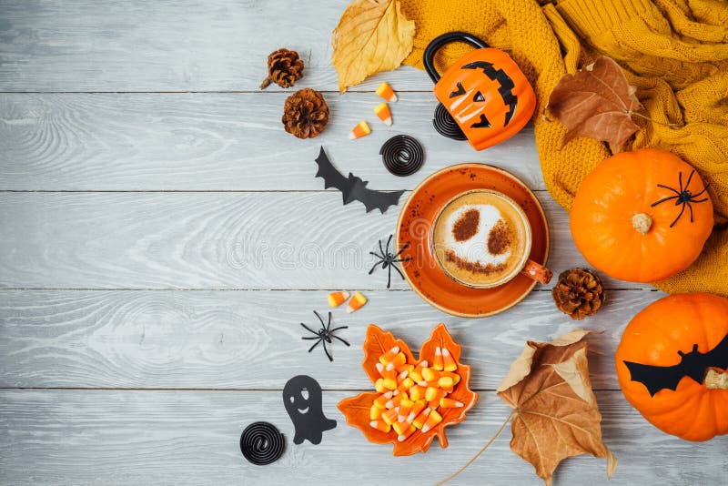 Halloween  holiday background with coffee cup, pumpkin and autumn leaves on wooden table. Top view from above. Flat lay