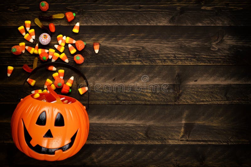 Halloween Jack o Lantern pail with side border of spilling candy over dark wood royalty free stock photo Halloween Jack o Lantern pail with side border of spilling candy over dark wood royalty free stock photo