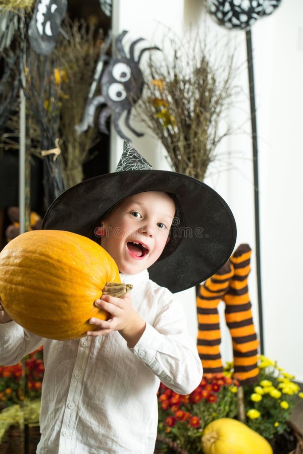 Halloween Kid with orange pumpkin in witch hat.