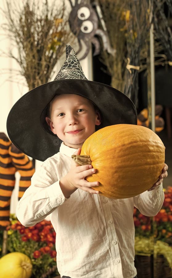 Halloween Kid with orange pumpkin in witch hat.