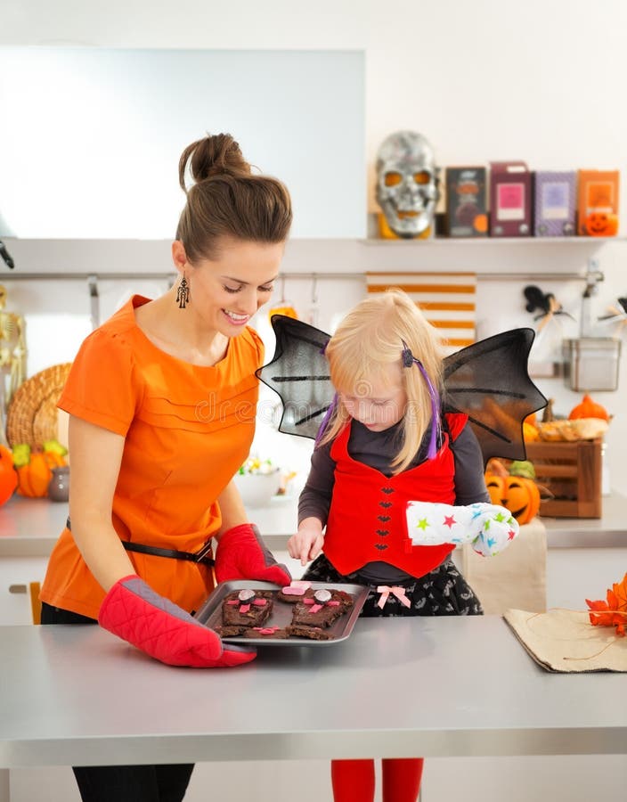 Halloween kleidete Mädchen mit der Mutter, die Behälter mit Keksen hält lizenzfreies stockfoto Halloween kleidete Mädchen mit der Mutter, die Behälter mit Keksen hält lizenzfreies stockfoto