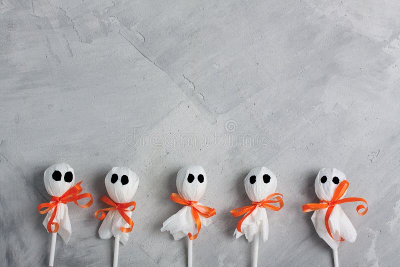 Halloween lollipop ghosts on gray concrete background