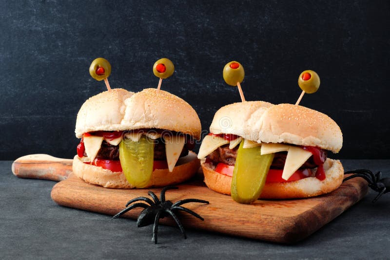 Halloween monster hamburgers on a paddle board against a black background. Halloween monster hamburgers on a paddle board against a black background