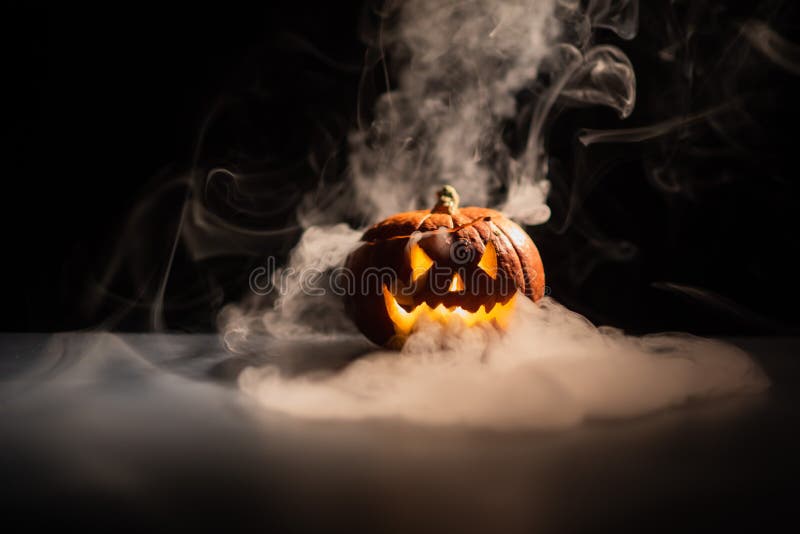Halloween, orange pumpkin with a scary luminous face on a dark background. Gray thick smoke comes out. Close-up of jack-o`-lanter royalty free stock photos Halloween, orange pumpkin with a scary luminous face on a dark background. Gray thick smoke comes out. Close-up of jack-o`-lanter royalty free stock photos