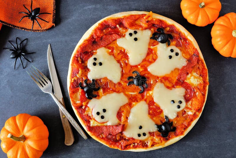 Halloween pizza with ghosts and spiders, above scene with decor on a black background. Halloween pizza with ghosts and spiders, above scene with decor on a black background