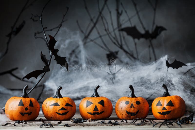 Halloween pumpkin heads with funny smile and spooky decoration on dark wood.