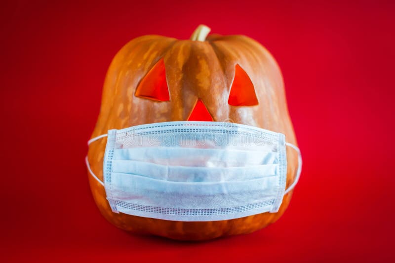 Halloween pumpkin in a protective medical mask on a red background.