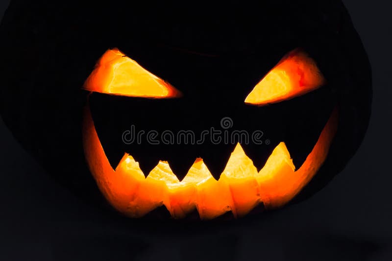Scary Halloween Pumpkin Head glowing at night, black background. (Jack-o'-lantern).