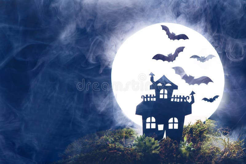 Halloween. Silhouette of an old house on a background of the full moon. Bats, fog