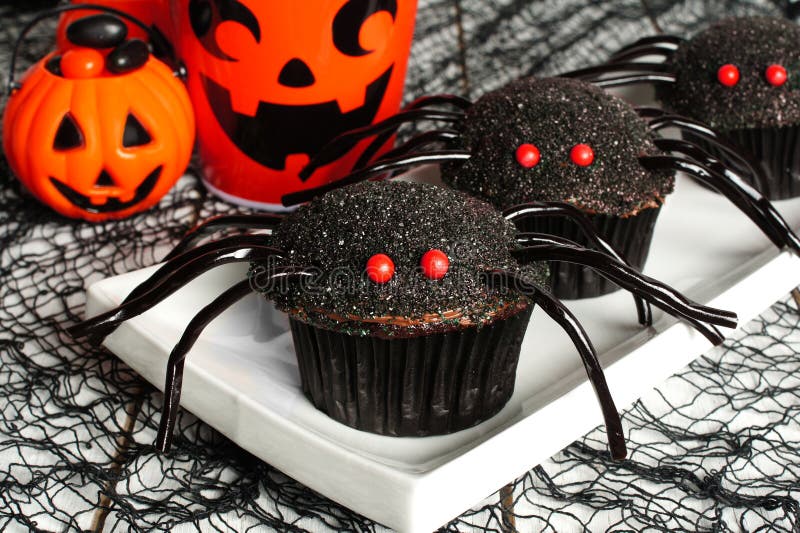 Halloween spider cupcakes on a white plate with holiday decor. Halloween spider cupcakes on a white plate with holiday decor