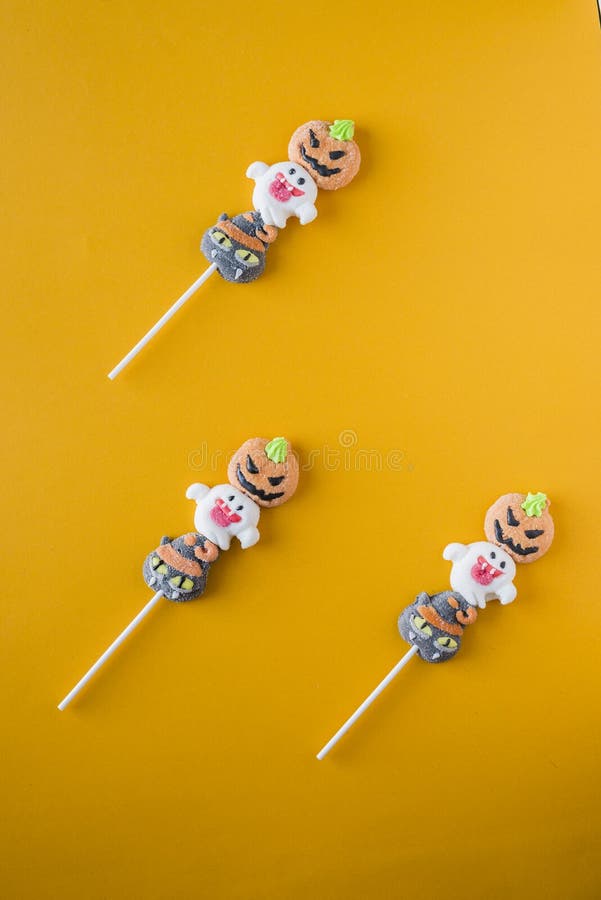 Halloween-suikergoed in een afwisselend patroon op een kleur wordt geschikt die stock afbeeldingen Halloween-suikergoed in een afwisselend patroon op een kleur wordt geschikt die stock afbeeldingen