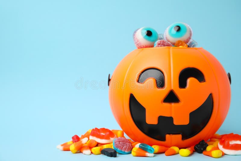 Halloween Trick or Treat Bucket with Different Sweets on Light Blue, Space for Text Stock Photo