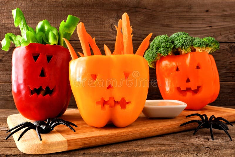 Halloween vegetables and dip in Jack o Lantern peppers on wood