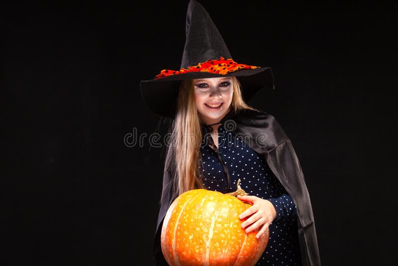Halloween Witch met pompoen op zwarte achtergrond Mooie jonge verraste vrouw in heksenhoed en kostuum vasthouden stock foto's Halloween Witch met pompoen op zwarte achtergrond Mooie jonge verraste vrouw in heksenhoed en kostuum vasthouden stock foto's