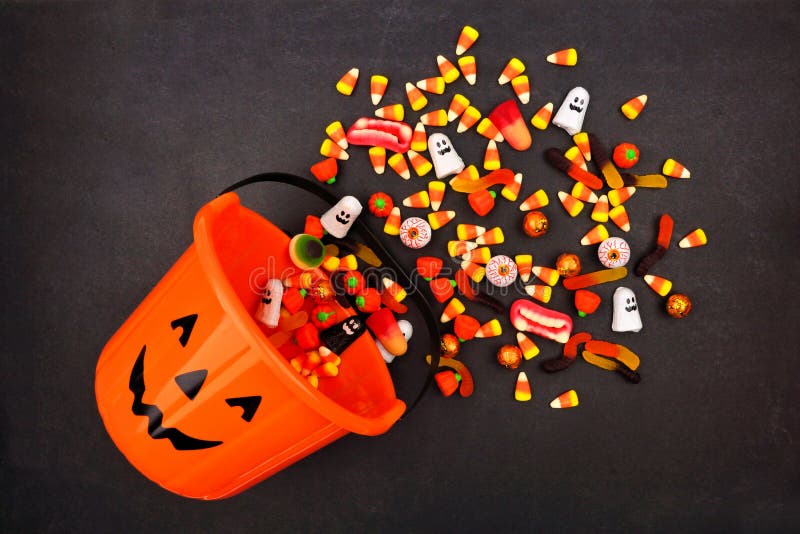 Halloween Jack o Lantern pail with spilling candy, above view on a dark background. Halloween Jack o Lantern pail with spilling candy, above view on a dark background