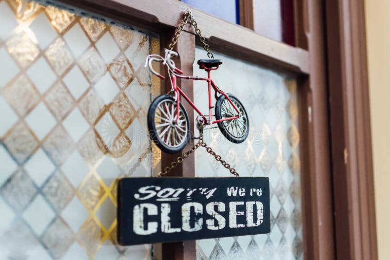HALLSTATT, AUSTRIA - DECEMBER 2018: door signboard saying Sorry we are closed with toy bicycle above stock photography HALLSTATT, AUSTRIA - DECEMBER 2018: door signboard saying Sorry we are closed with toy bicycle above stock photography