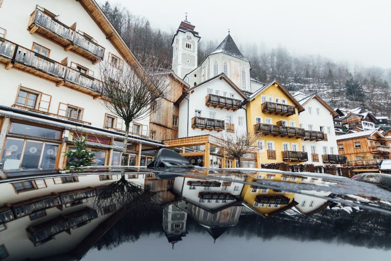 HALLSTATT, ÖSTERREICH - JANUAR 2019: Reflexion von alten Reihenhäusern im Autodach stockbild HALLSTATT, ÖSTERREICH - JANUAR 2019: Reflexion von alten Reihenhäusern im Autodach stockbild