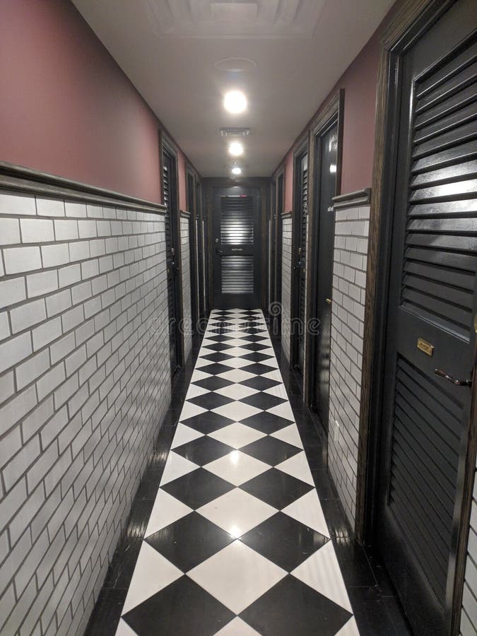 Hallway with a Black and White Floor and Doors Under the Lamp Lights