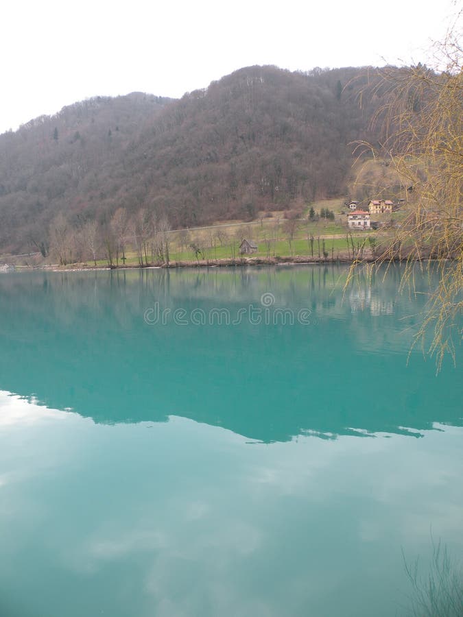 Halny jezioro z turkusową błękitne wody, otaczającą alps i zielonymi wzgórzami Pełny pokój Spokojna woda odbija miasto na coa fotografia stock Halny jezioro z turkusową błękitne wody, otaczającą alps i zielonymi wzgórzami Pełny pokój Spokojna woda odbija miasto na coa fotografia stock