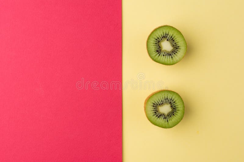 Halva-snitt kiwi på en pastellfärgad guling och en röd bakgrund Top beskådar arkivbilder