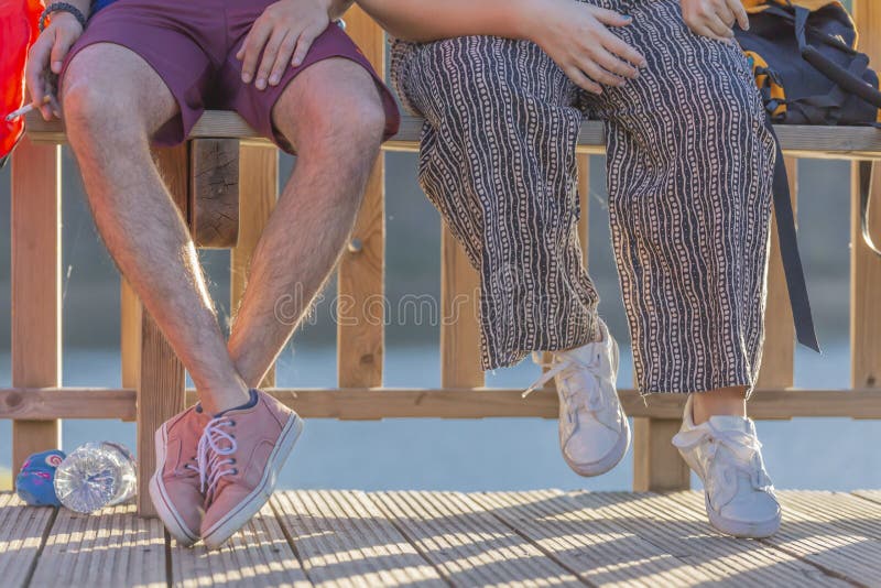 Halve lichaamsmening, bodem, jonge paarzitting over een houten bank, hij die een sigaret roken stock afbeeldingen Halve lichaamsmening, bodem, jonge paarzitting over een houten bank, hij die een sigaret roken stock afbeeldingen