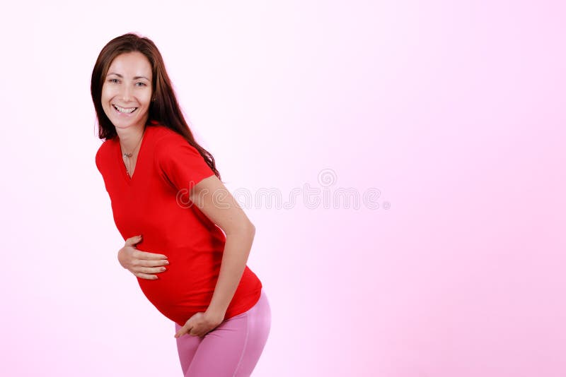 Halvlängdporträtt av vacker kaukasisk ung gravid modell med ömhet rör hennes mage. gravid glad modern