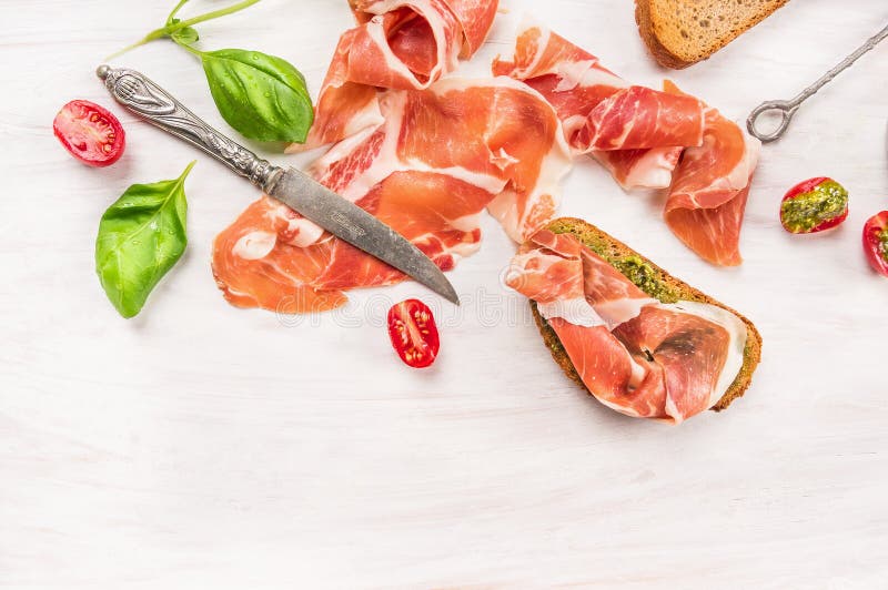 Ham with toast,knife, Basil and pesto on white wooden background