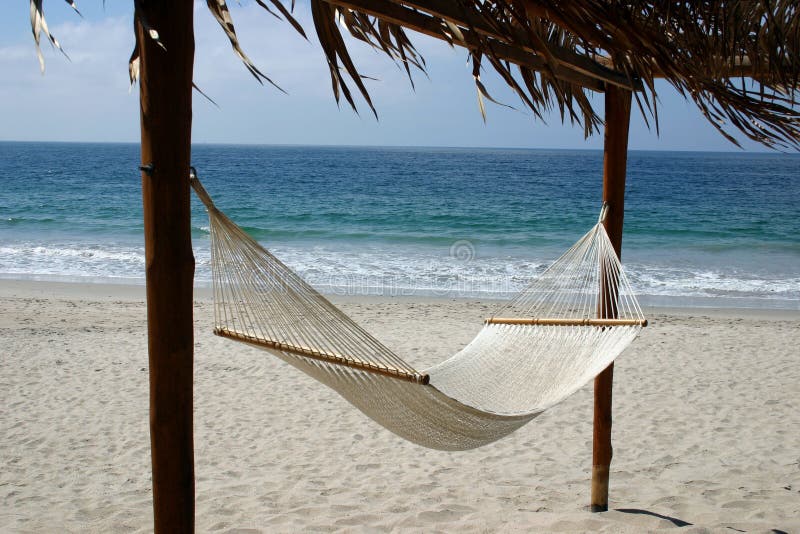 A hammock overlooking a sandy beach and a deep blue ocean. A hammock overlooking a sandy beach and a deep blue ocean