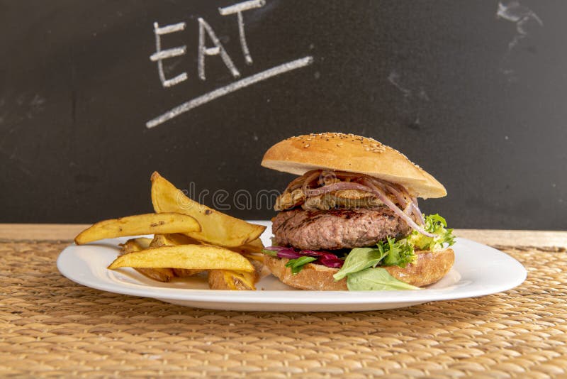 Hambúrguer com ovo frito e batata frita em um fundo preto, em um