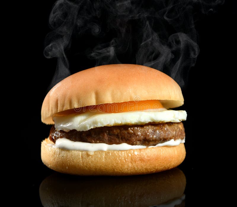Hambúrguer com ovo frito e batata frita em um fundo preto, em um