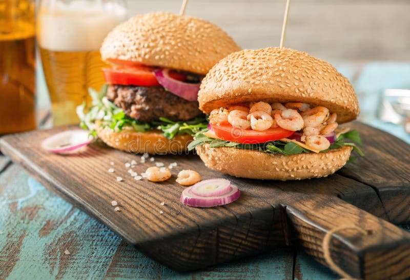 Hamburgare med den grillade räka- och nötköttlilla pastejen med ljust öl royaltyfria bilder Hamburgare med den grillade räka- och nötköttlilla pastejen med ljust öl royaltyfria bilder