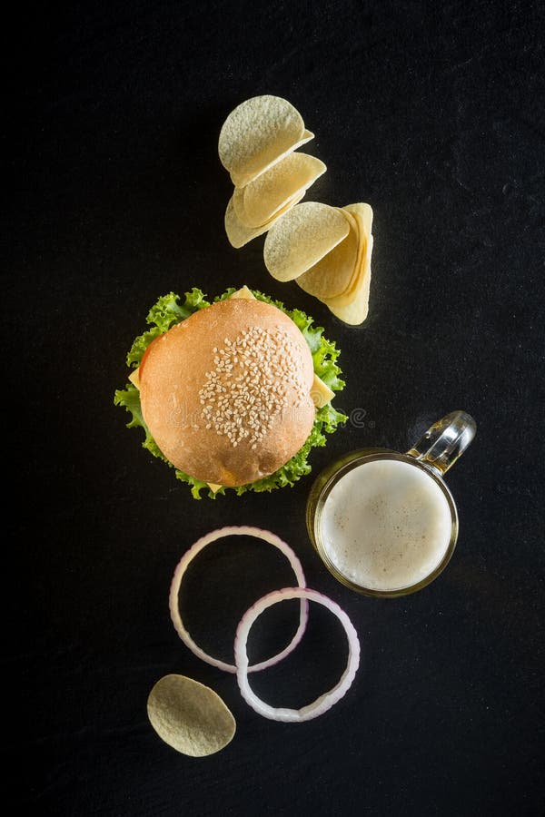Hamburgare med en råna av kallt öl, ketchup och frasiga chiper på D arkivbild Hamburgare med en råna av kallt öl, ketchup och frasiga chiper på D arkivbild