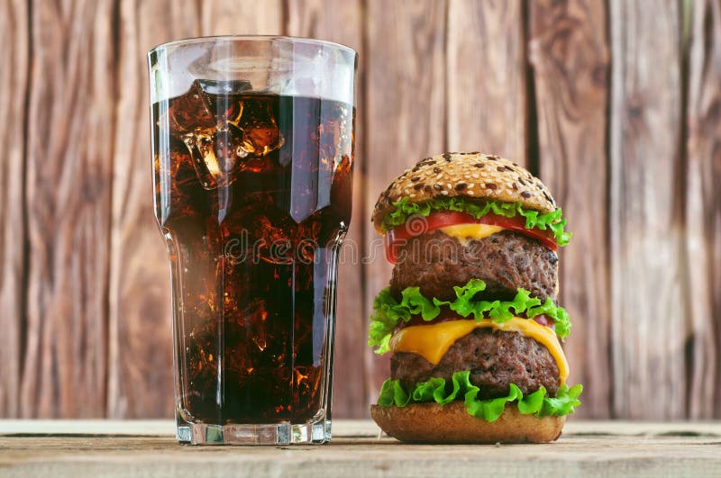 Hamburger, cola with ice on a wooden background