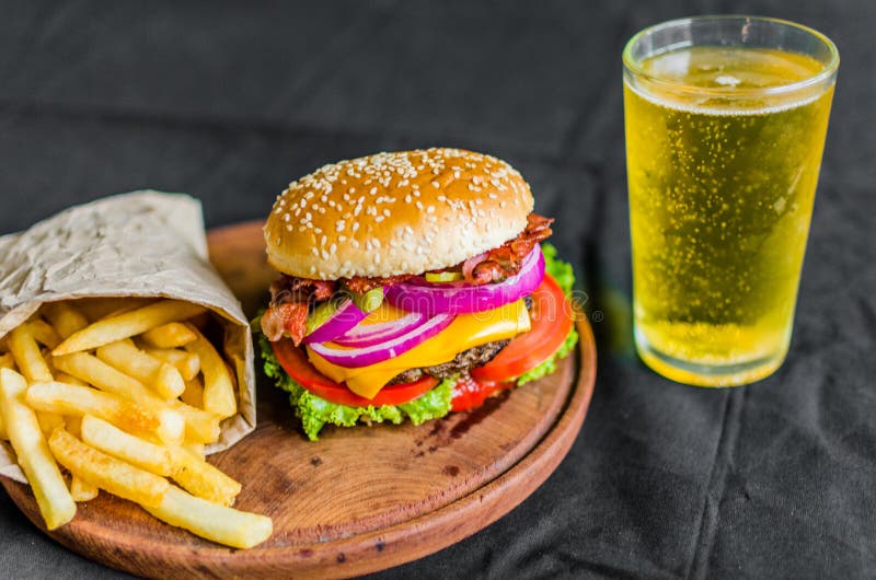 Hamburger e patate fritte su una tavola di legno contro fondo nero