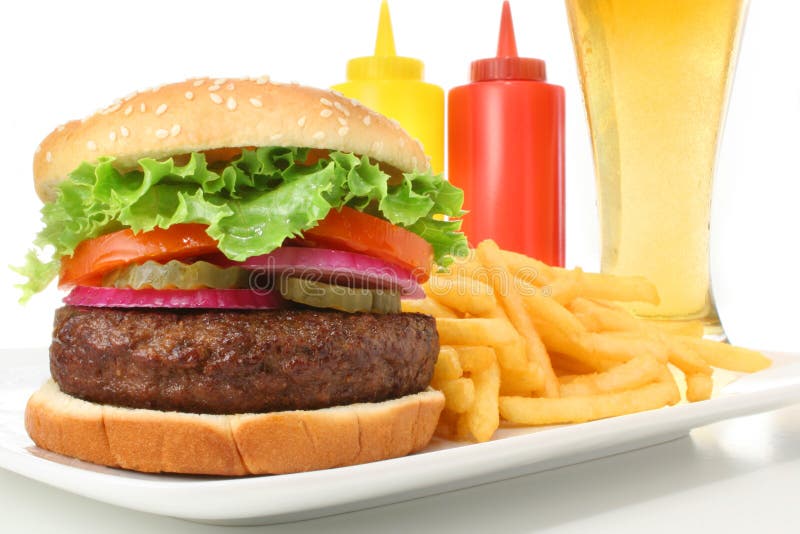 Hamburger su una piastra con patatine fritte, ketchup e senape contenitori e un bicchiere di birra isolato su sfondo bianco.